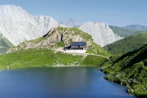 Die Wolayersee Berghütte mit dem Wolayer Bergsee im Vordergrund; (c) Wolayerseehütte/Wikimedia